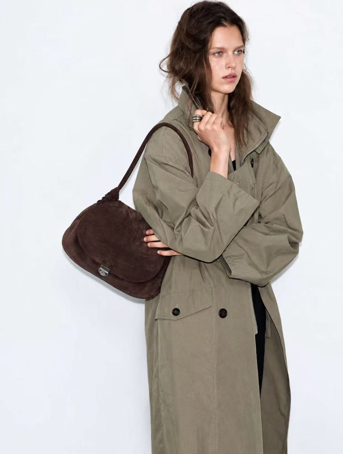 Woman carrying a brown leather bag outdoors